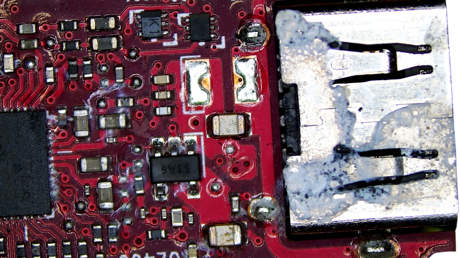 Liquid-damaged computer motherboard with visibly deteriorated circuit paths and electronic components