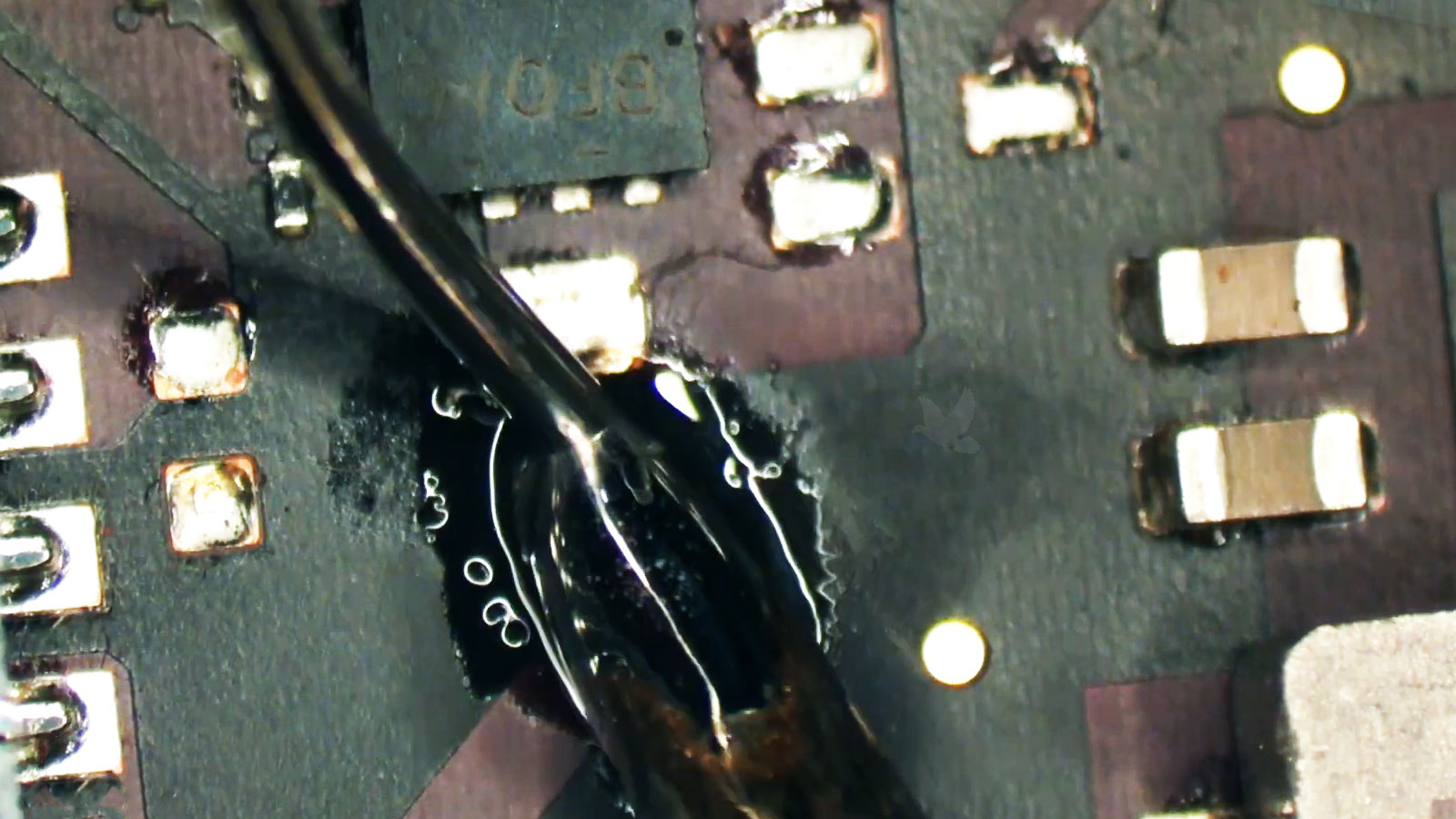 Solder being applied to MacBook Pro logic board pads before installing a replacement component