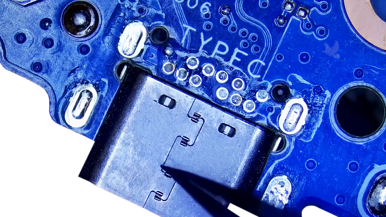 USB-C port held with tweezers over the Type-C connection points during laptop motherboard repair