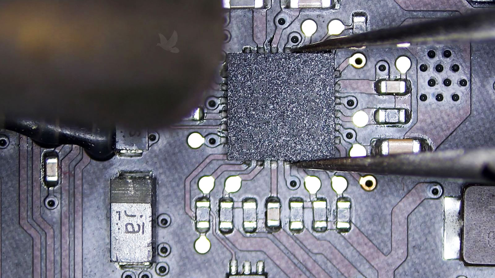 Damaged IC chip being removed from a MacBook Pro logic board with hot air and tweezers
