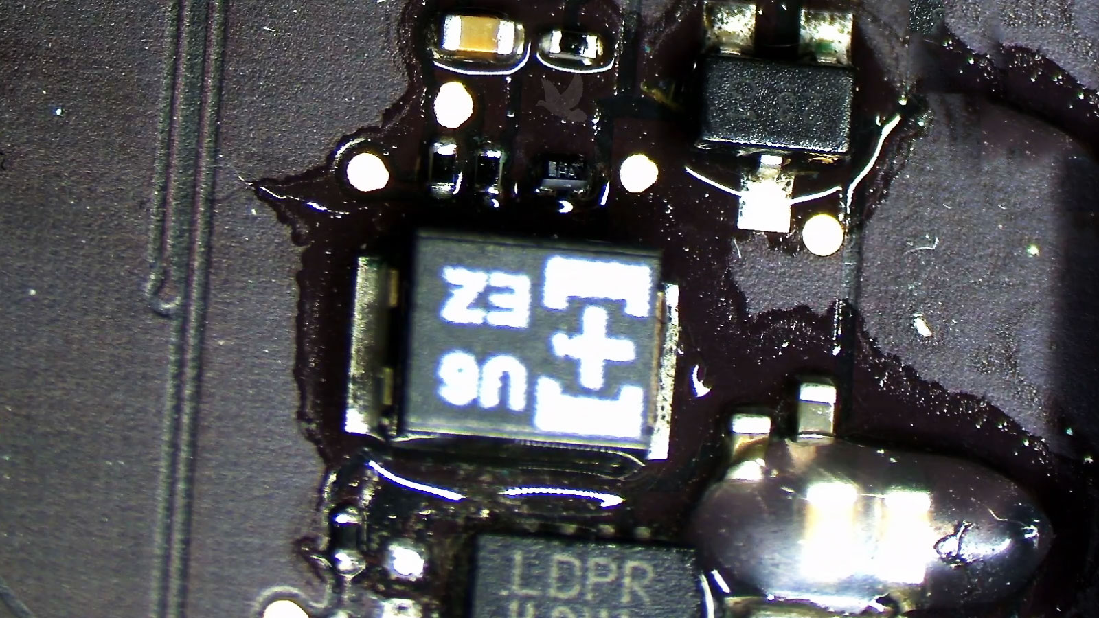 MacBook Pro repair in progress showing visible liquid residue and damage around motherboard components