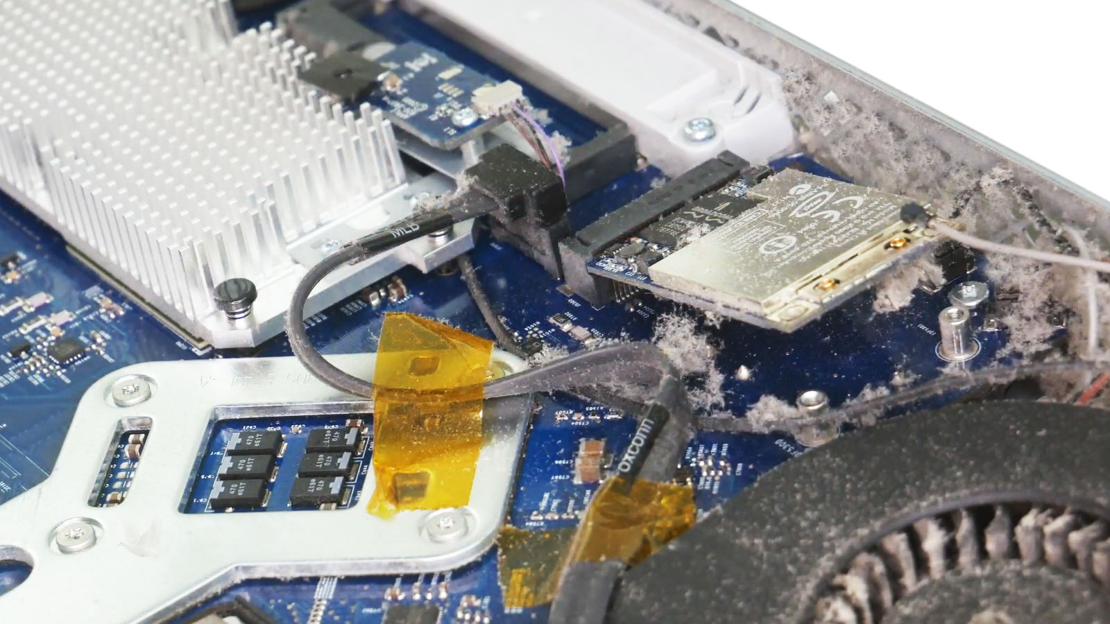 Open iMac showing heavy dust and debris buildup around the cooling fan vents and internal components