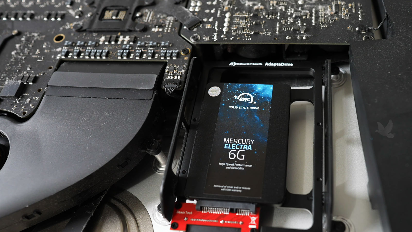 Open iMac with an installed SSD adapter, logic board, and CPU cooling fan exposed for diagnostic testing