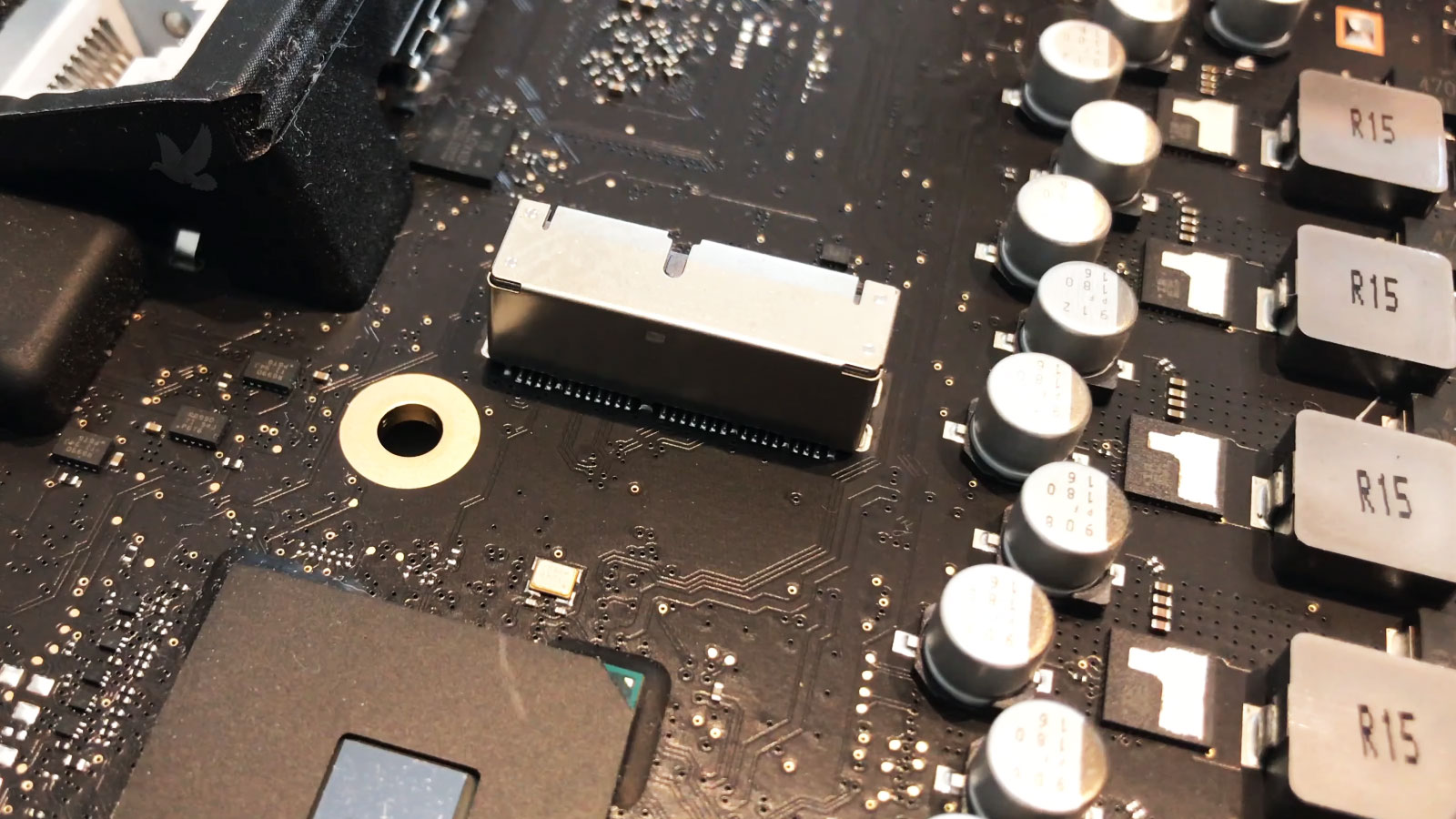 iMac logic board with shorted MOSFETs near the M.2 SSD connection being diagnosed for repair