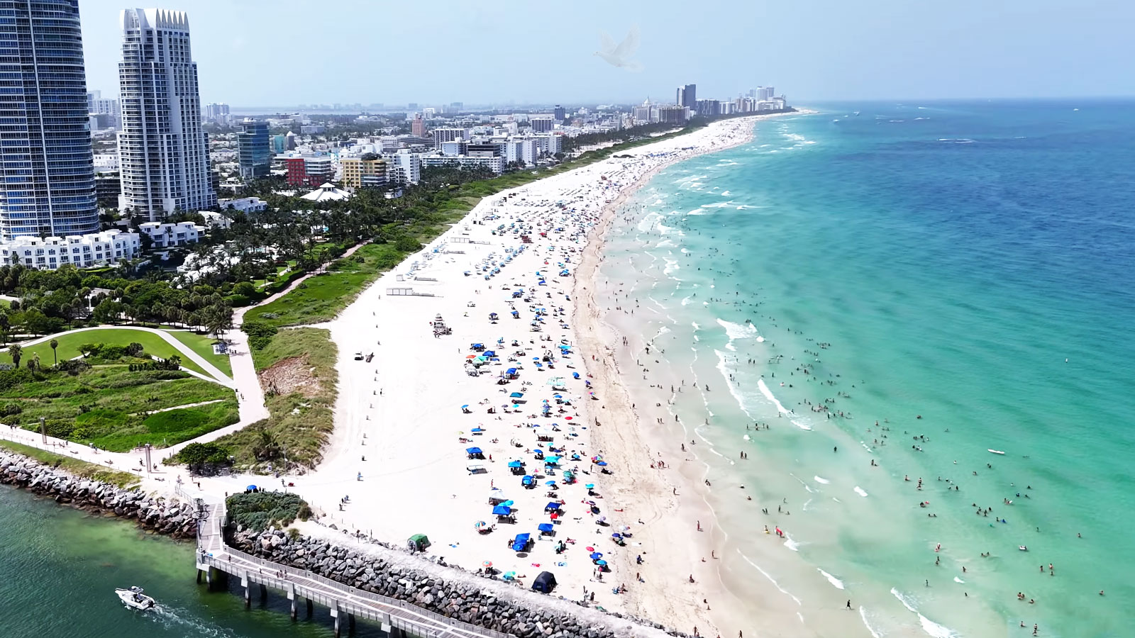 Crowded South Beach shoreline in Miami Beach with high-rise buildings in the distance
