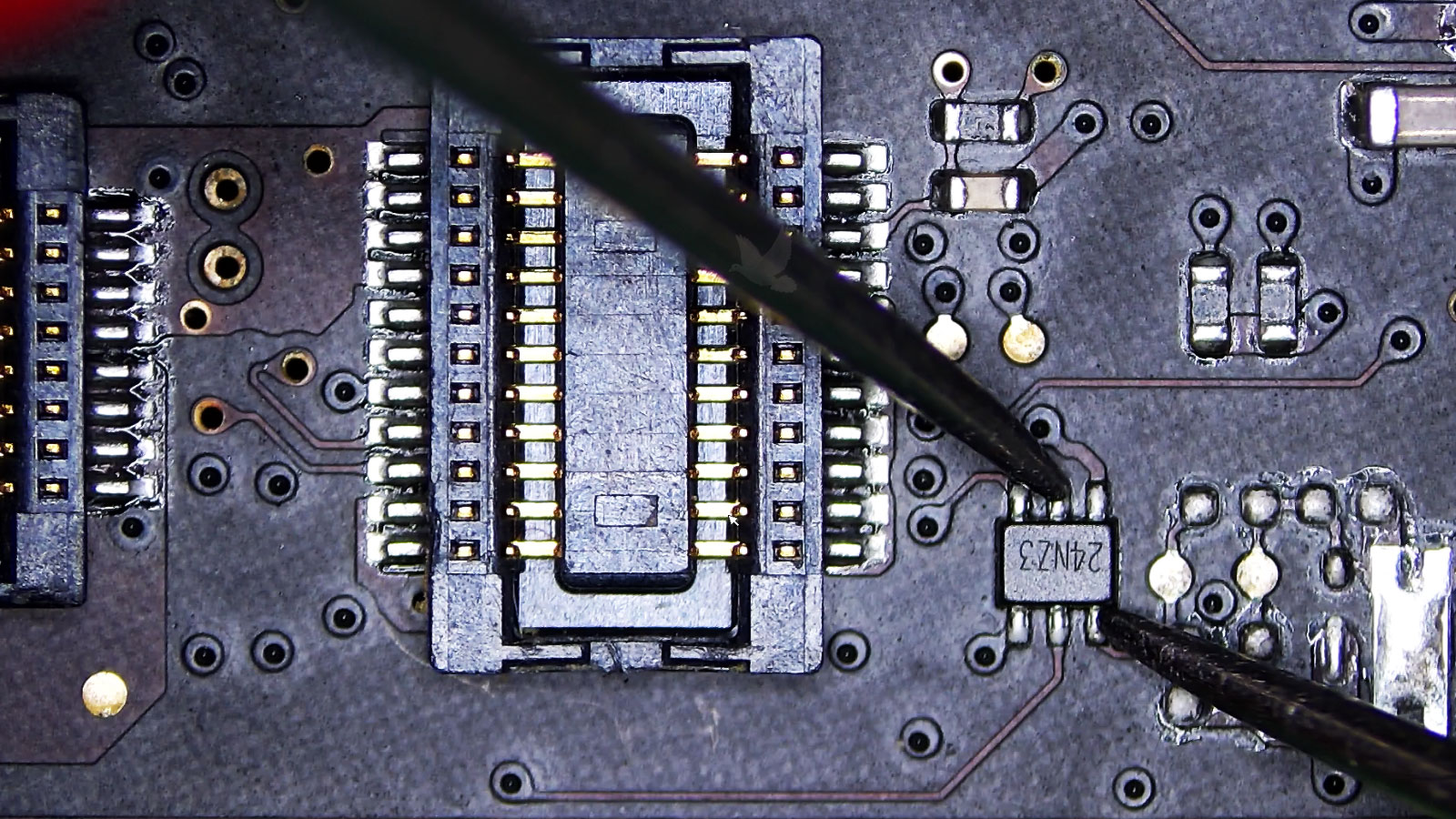 Six-pin IC marked 24NZ3 being measured for low resistance near multiple connectors on a computer circuit board