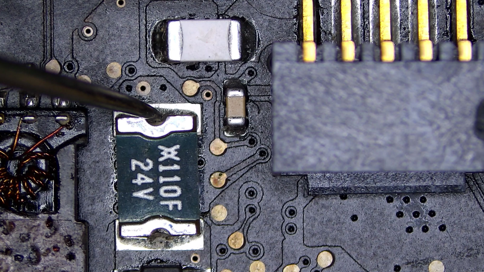 Probe measuring one end of a 24-volt 1110F fuse while the opposite side is checked elsewhere on the same rail