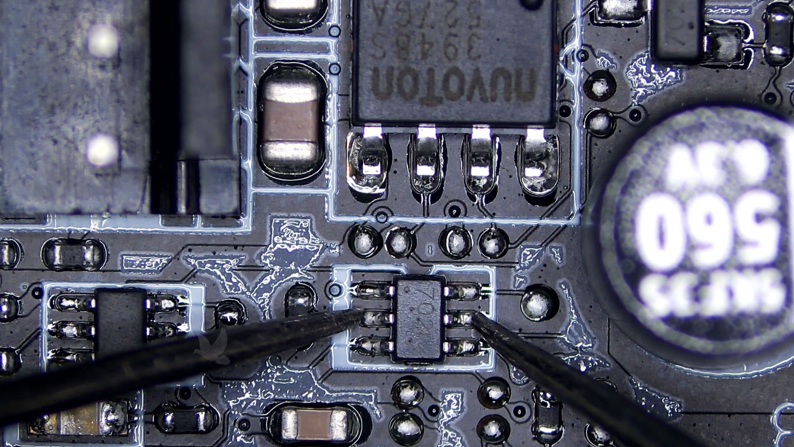Six-pin 702N IC being measured between center pins during motherboard diagnosis