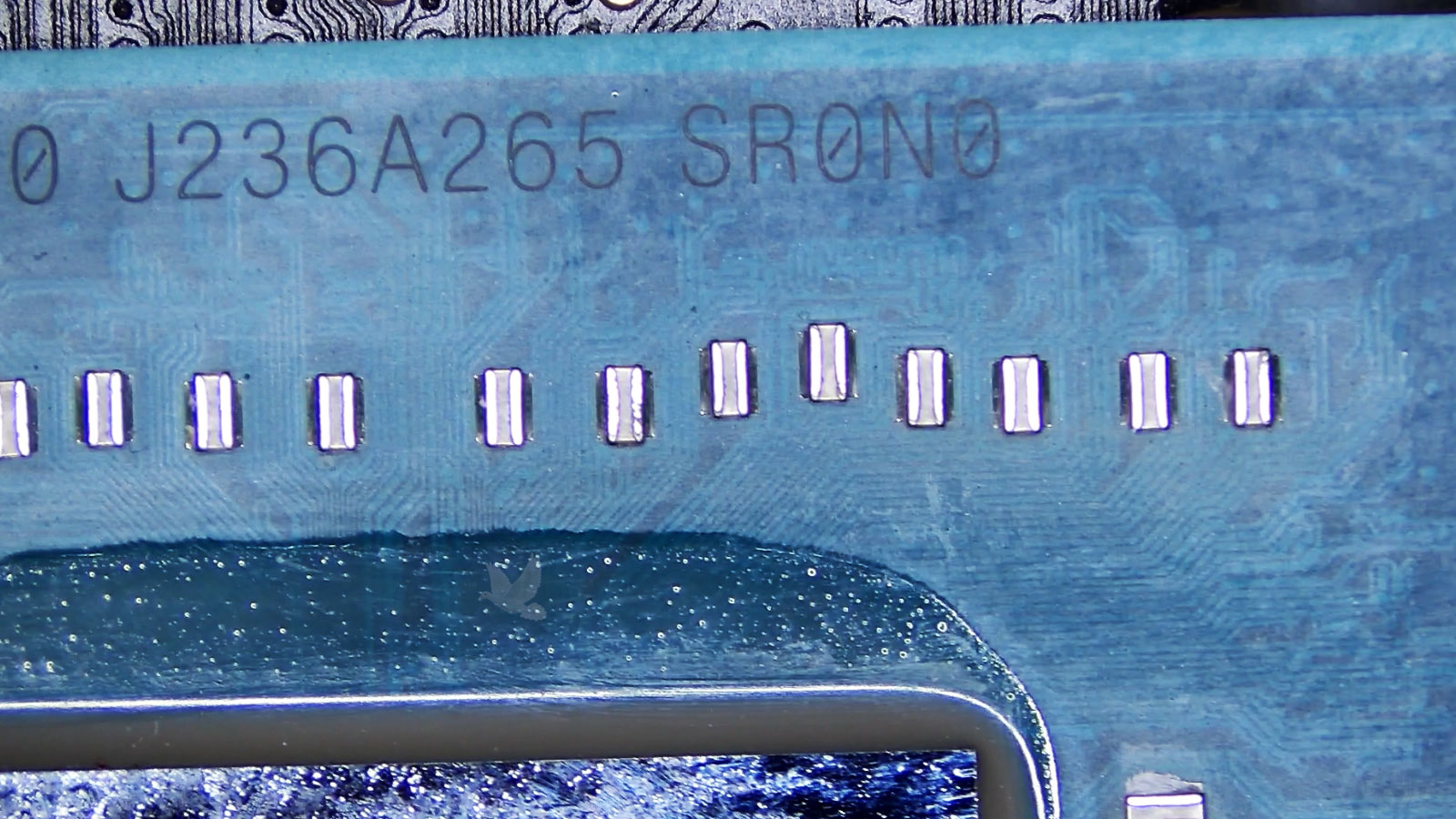 Damaged surface-mount capacitor on top of a CPU being inspected for replacement