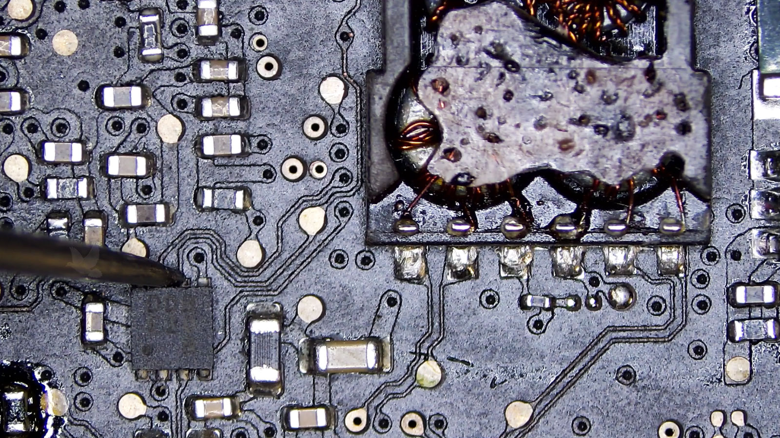 Probe measuring a shorted pin on a controller beside a visibly damaged IC