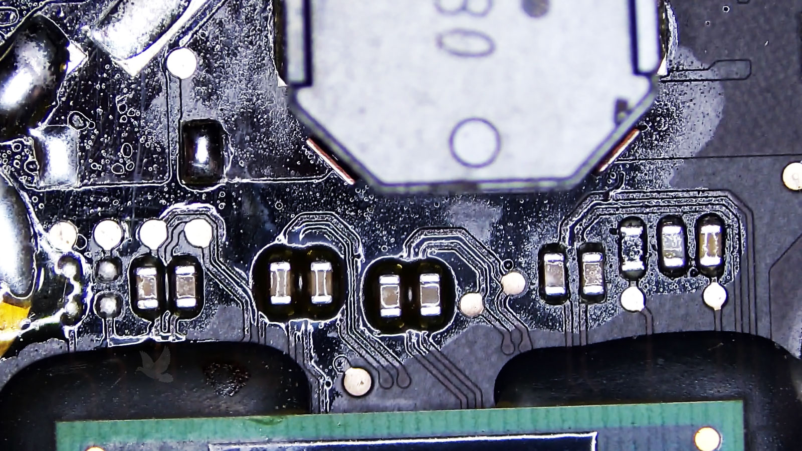 Dried sticky liquid residue covering components in a damaged circuit board section