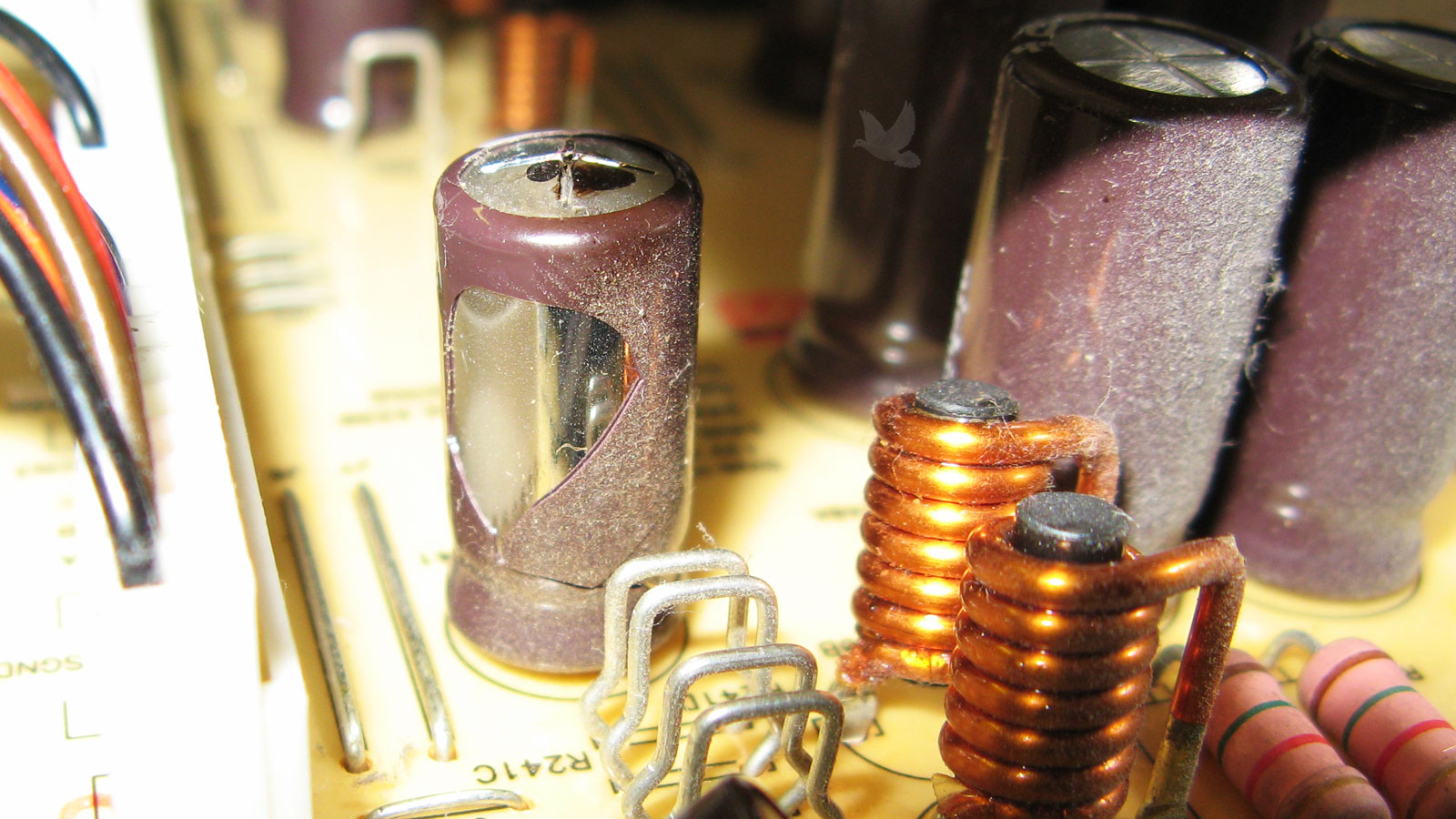 Bulging electrolytic capacitor with black residue leaking from exploded top