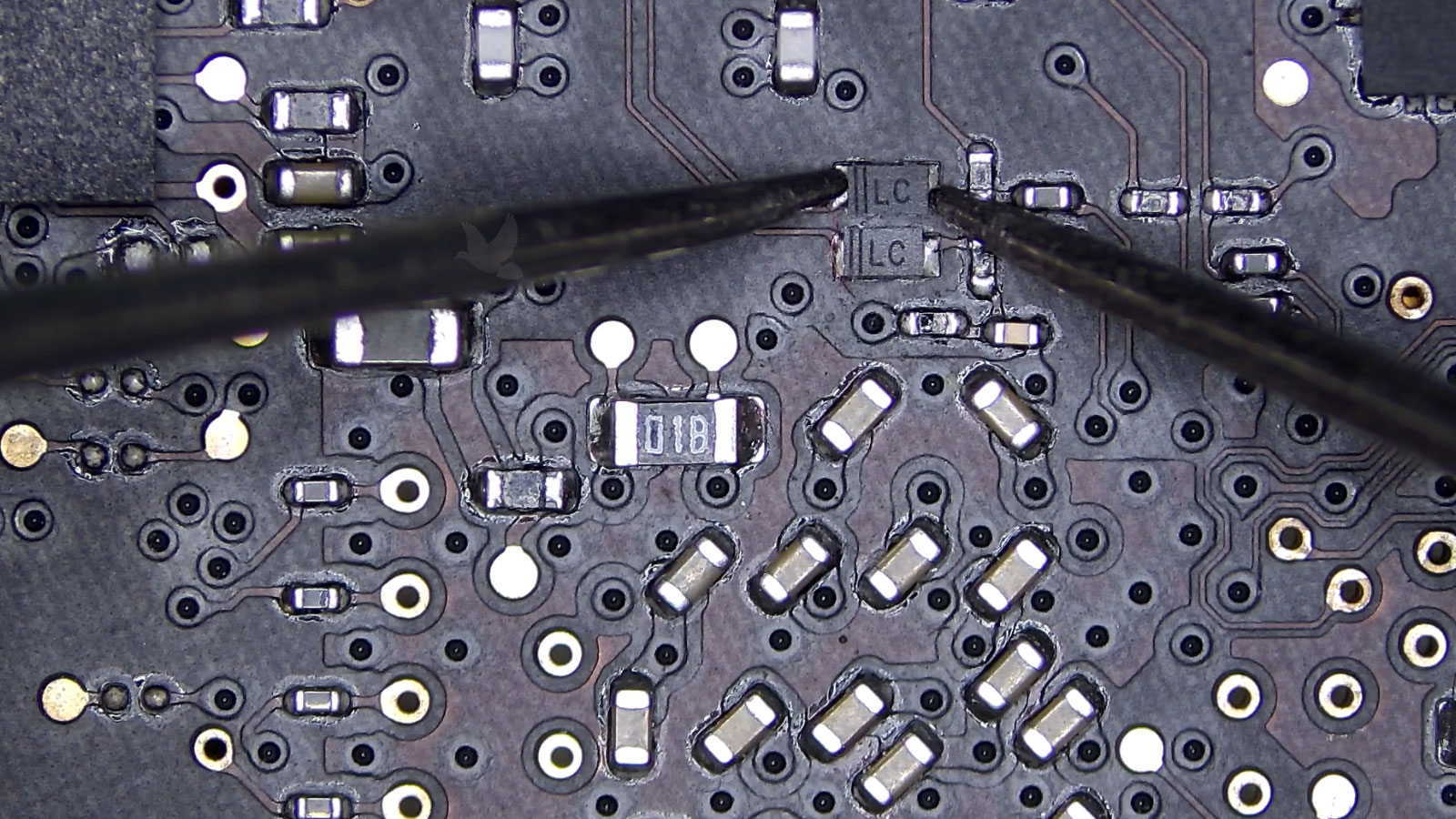 Faulty diode being measured beside an adjacent diode with a different reading on a computer circuit board