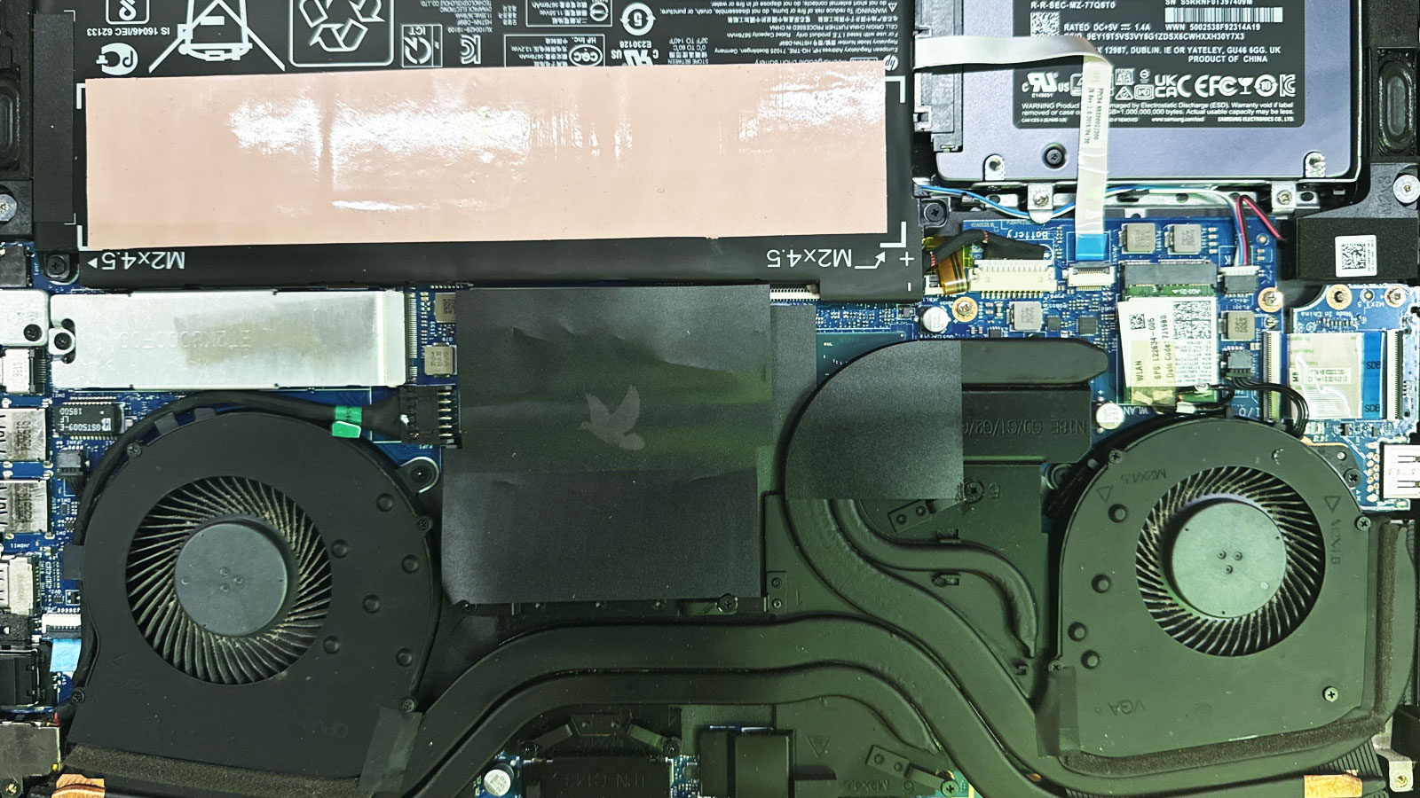 Gaming laptop motherboard fully reassembled after repair, with heatsink, SSD, and internal cables properly connected.