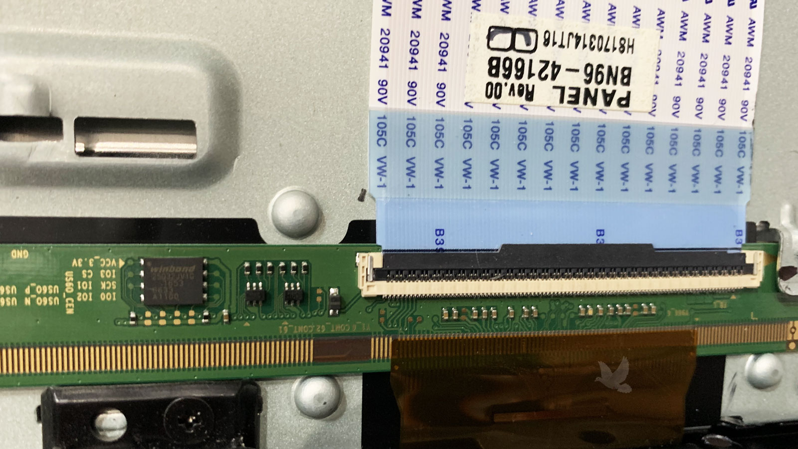 LCD panel flex cable connected to a display circuit board where a shorted SMD capacitor was repaired to restore normal screen operation.