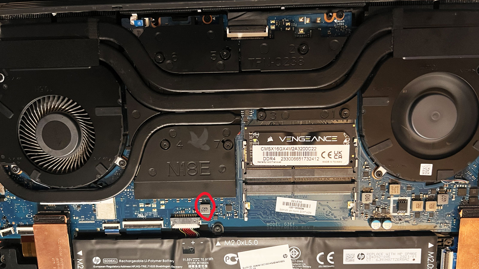 Laptop motherboard showing the right cooling fan running at full speed while the left fan is not spinning, with a red circle identifying a 4R7 coil where no voltage is detected.