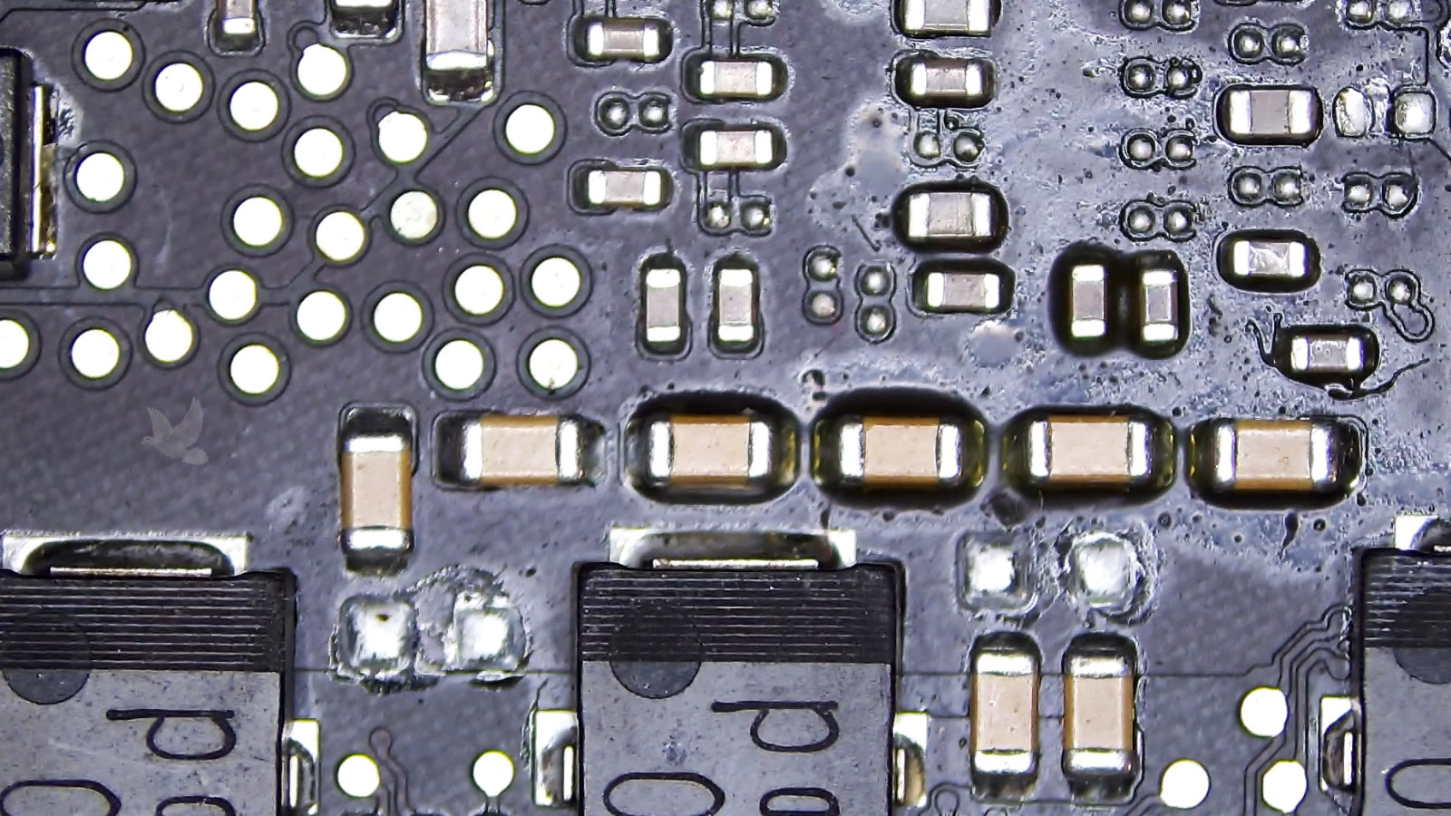 Multiple capacitors of different sizes exposed to liquid residue on a circuit board