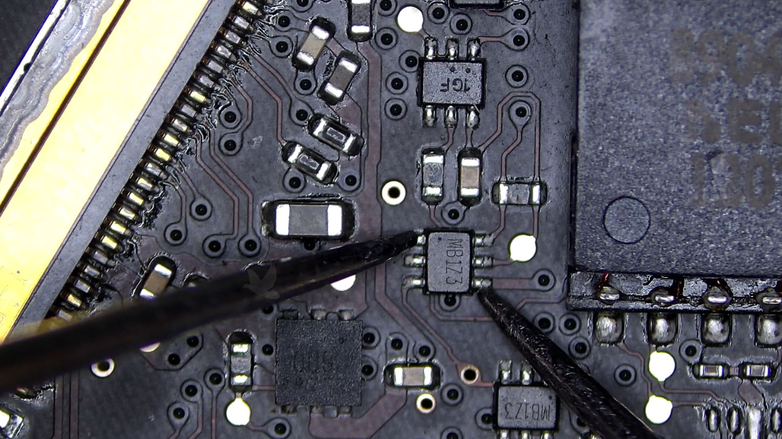 MB123 six-pin IC being measured next to an LCD screen connector on a computer circuit board