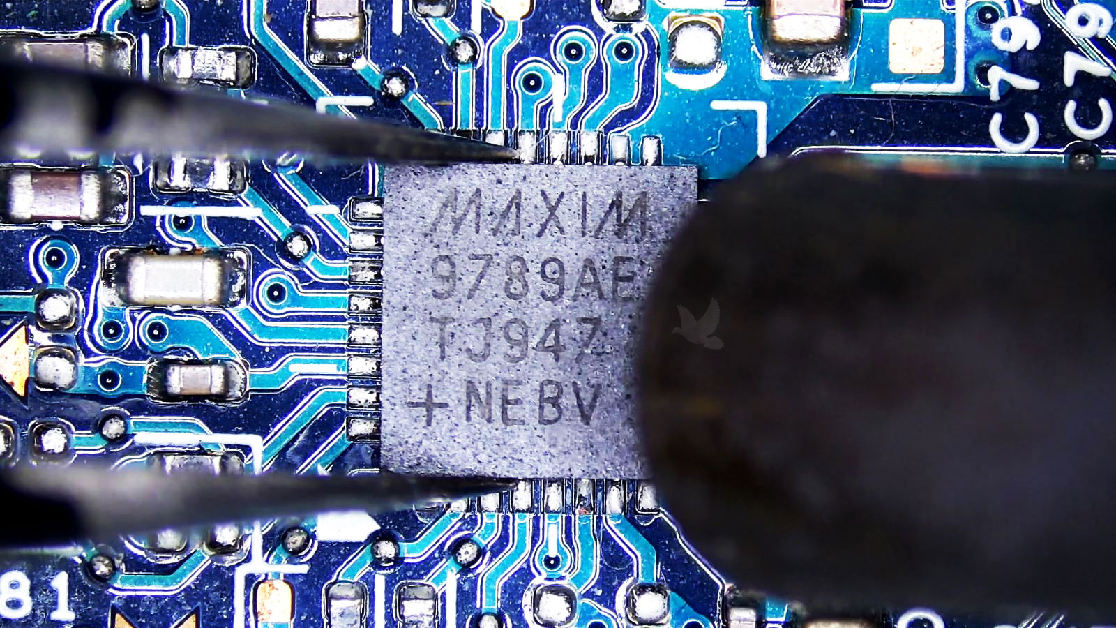 Maxim IC chip held with tweezers during hot air removal after a nearby capacitor failure