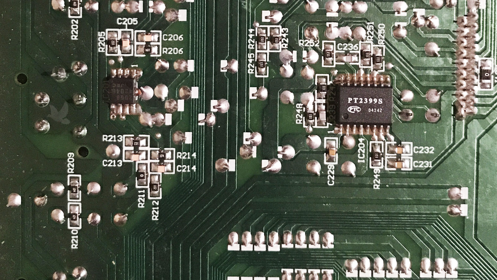 Back of a circuit board showing cracked solder joints associated with a PT2399S integrated circuit, repaired by resoldering to restore proper operation.