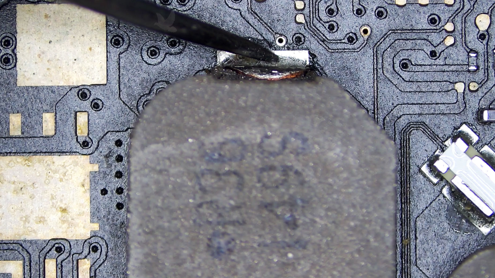 Rusty motherboard coil being measured for resistance during circuit diagnostics