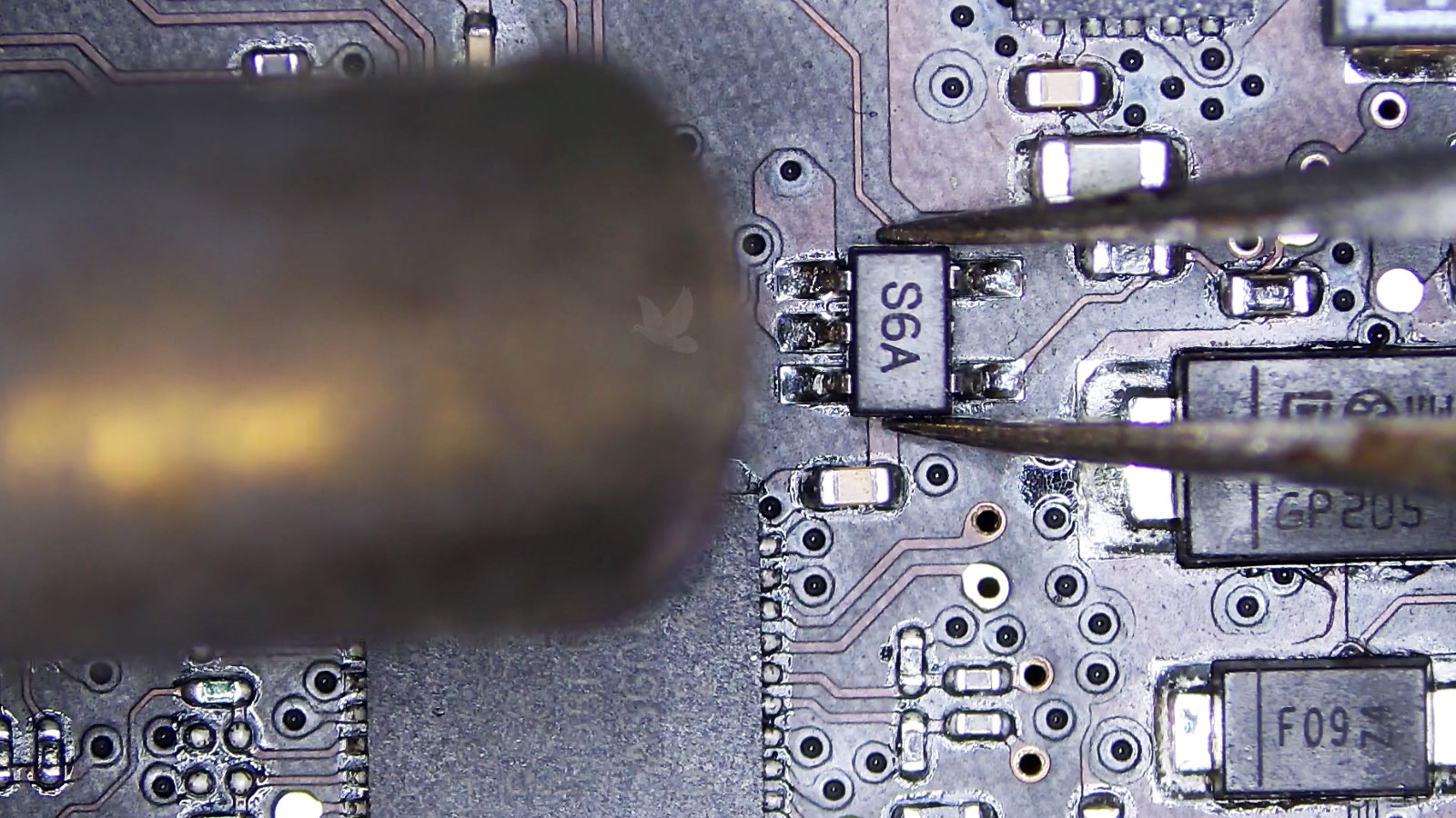 Shorted S6A transistor held with tweezers while being removed from a computer circuit board using hot air