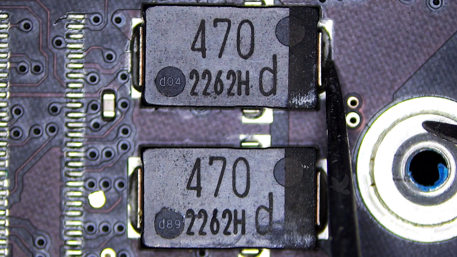 Two 470 SMD capacitors being measured from the positive side to ground on a computer circuit board