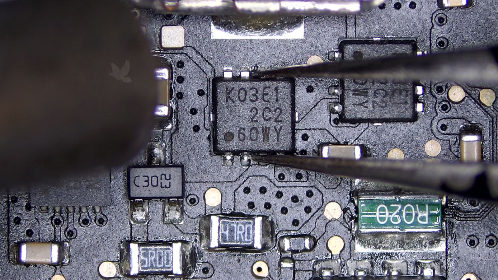 Tweezers holding a shorted K03E1 MOSFET while a hot air rework gun is used for removal